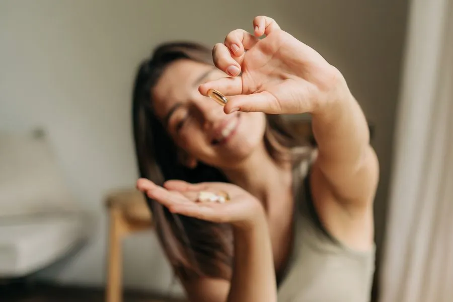 A woman holding a supplement in front of her face.
